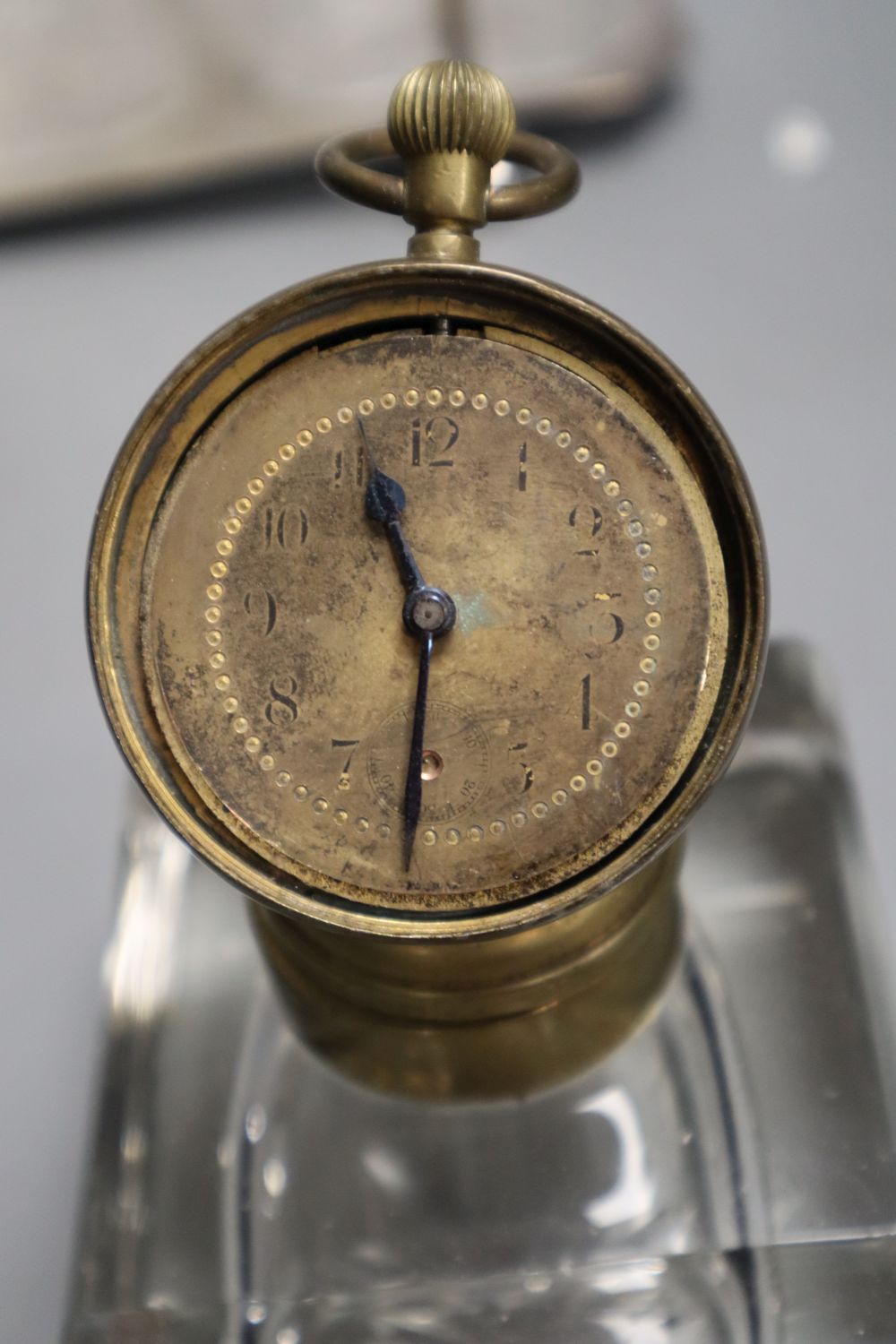 A late 19th century combination desk timepiece / inkwell, hinged timepiece on cut glass well, together with a three decanter tantalus